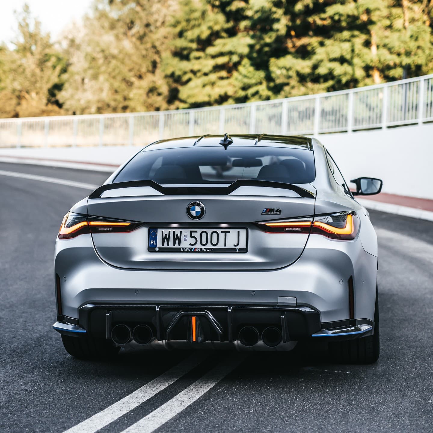 Srebrne BMW M4 G82 z elementami Carbonite, ujęcie od tyłu